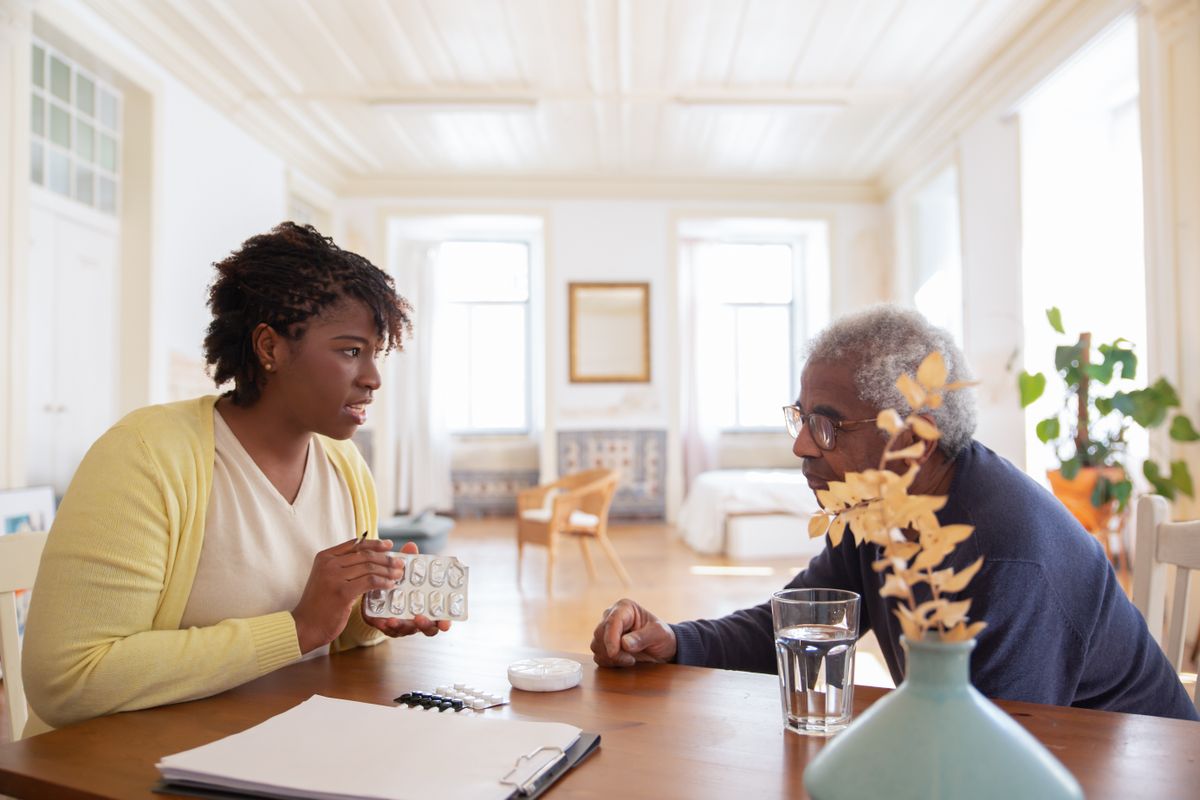 A caregiver reviewing medicines with an older man at home